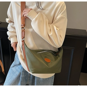 Detail of dark green crescent bag featuring a brown leather strap and silver zipper