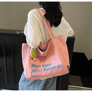 Detail of pink canvas tote with blue embroidery and black-and-white striped inner lining