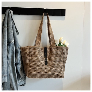 Détail du sac cabas en paille tressée avec bandoulière en cuir noir et boucle métal