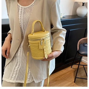 Close-up of bright yellow embossed leather bucket bag with textured pattern on a model