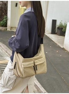 Detail of khaki canvas messenger bag featuring utility pockets and adjustable black strap