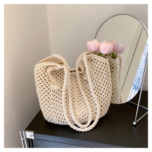 Detail of hollow mesh knit tote bag with tassel trim and sturdy braided handles
