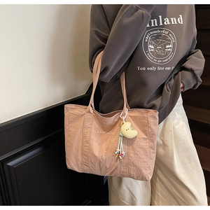 Detailed view of light pink tote bag with moon charm and white embroidery