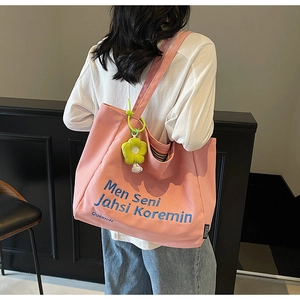 Pink canvas tote bag with blue embroidery and yellow flower pendant on model's shoulder