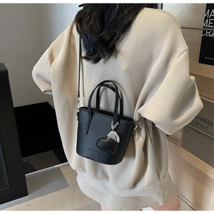 Detail of black pebbled leather bucket bag with heart charm and shoulder strap