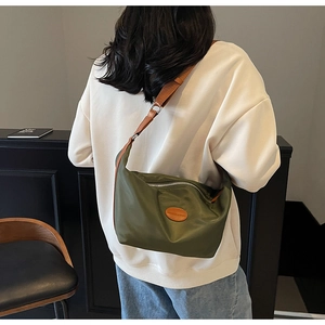 Detail of army green nylon crossbody bag with brown leather strap and fashion patch