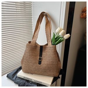 Détail du cabas en paille tissée avec lanière en cuir noir et boucle en métal doré