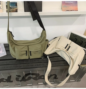 Detail of olive green and off-white canvas messenger bags with dual utility front pockets