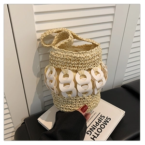 Detail of hand-woven straw bucket bag featuring a white decorative ring chain handle