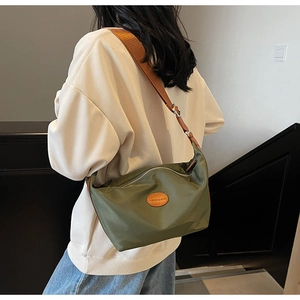 Detail view of army green nylon half-moon bag with fashion leather tag and wide strap