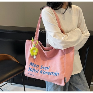 Close-up of pink canvas tote bag with blue embroidery and a yellow flower charm
