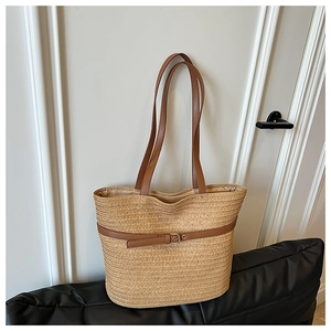 Detail of woven straw tote bag featuring brown faux leather straps and buckle strap detail