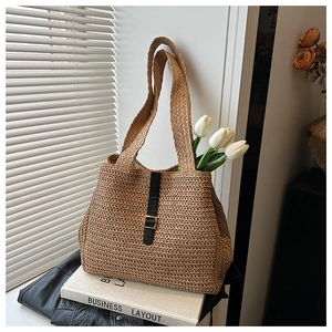 Détail de la texture tressée kaki naturelle et de la boucle en cuir noir du sac de plage