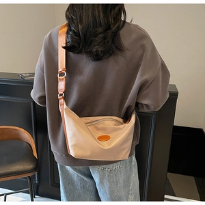 Model view of beige oxford nylon dumpling crossbody bag with brown wide fabric strap