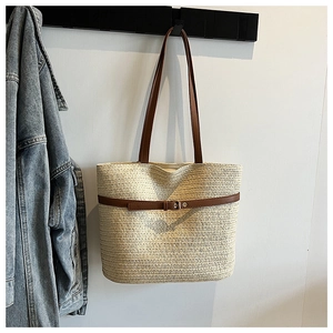 Detailed weave of beige straw tote bag featuring dark brown leather handles and buckle