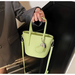 Detail of green lychee leather bucket bag with heart pendant and embossed logo