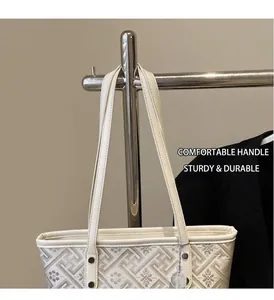 Dettaglio della borsa tote in jacquard beige con motivi geometrici e manici in pelle