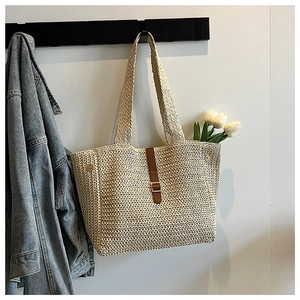 Détail du sac cabas en paille avec boucle en cuir marron et fermoirs métalliques