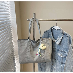 Detail of grey canvas tote bag with yellow moon plush charm and colorful fringe accessory