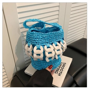 Close-up of blue woven bucket bag with white chain details and braided handle