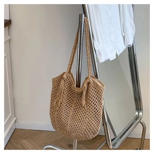 Detail of khaki woven tote bag with hollow mesh pattern and side fringe tassels