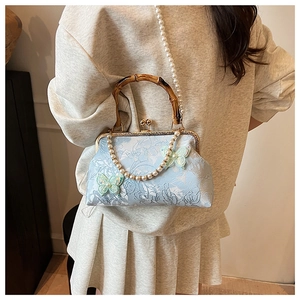 Detail of light blue jacquard shell bag with bamboo handle and 3D butterfly appliqué