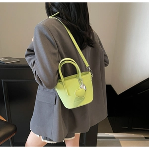 Lime green litchi texture bucket bag with heart pendant shown on a grey suit model