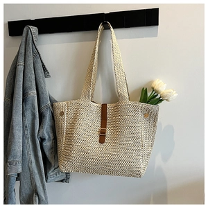Détail du cabas en paille tressée beige avec sangle en cuir et boucle en métal dorée