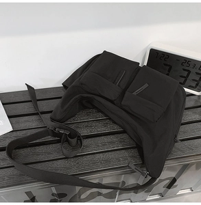 Detail of durable black nylon crossbody bag featuring utility multi-pockets and plastic buckle