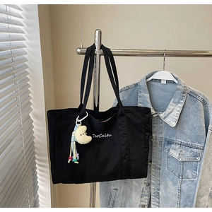 Detail of black canvas tote bag with TaoCaitu print and yellow plush crescent moon charm