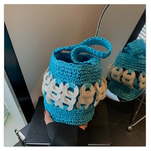 Close-up of blue hand-woven bucket bag with white ring accents and fabric lining