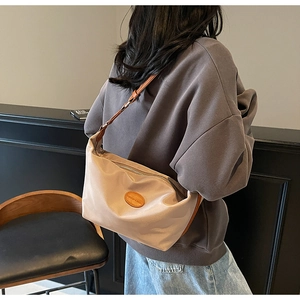 Detail of adjustable leather strap and nylon dumpling bag on a stylish female model