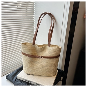 Detail of woven straw tote bag with brown leather handles on white shutter background