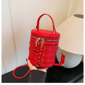 Detail of red cylinder bag with quilted bear pattern and golden zipper closure