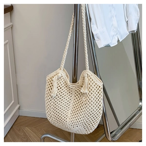 Detail shot of cream woven tote bag showing cotton rope mesh and fringe tassels