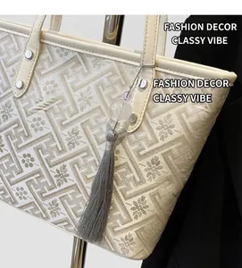 Dettaglio della borsa tote jacquard con motivo geometrico ed elegante ciondolo a nappa grigia