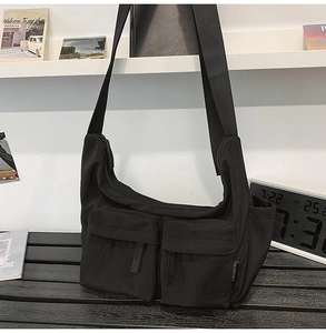 Close-up of a black nylon crossbody bag with dual front pockets and adjustable straps