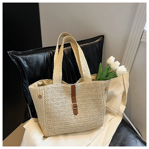 Détail du sac fourre-tout en paille tissée avec lanière en cuir marron et boucle