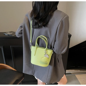 Detailed close-up of neon green lychee grain leather bucket bag with heart pendant and strap