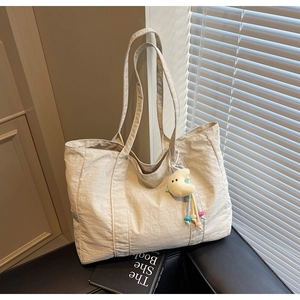 Detail of beige nylon tote bag with plush moon charm and delicate embroidery text