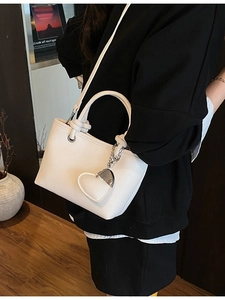 Elegant white lychee leather bucket bag with silver chain and heart charm accessory