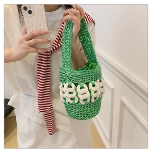 Close-up of bright green woven bucket bag with decorative white rings and woven handle