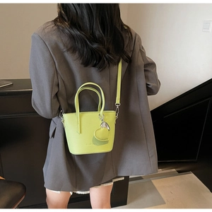 Detailed back view of a bright green mini bucket bag with a heart charm and strap