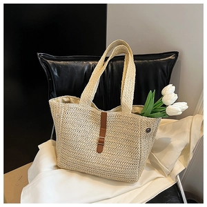 Détail du sac cabas en paille beige avec lanière en similicuir brun et fermoir aimanté