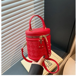 Detail of red cylinder bucket bag with litchi grain leather and animal embossed patterns