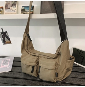 Detail view of khaki messenger bag with multiple pockets on a stylish desktop setup