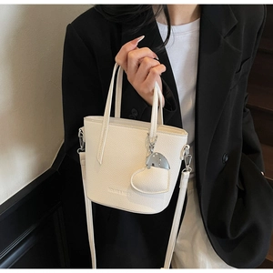 Detailed macro view of white lychee pattern leather bucket bag with heart mirror charm