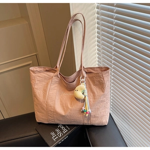 Close-up of pink nylon tote bag with white TaoCai print and moon charm accessory