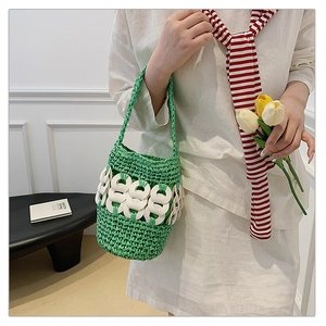 Detail of hand-woven green straw bucket bag featuring stylish white acrylic ring buckles