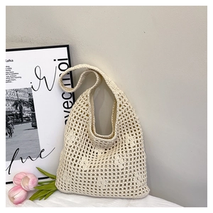 Detail view of beige hand-woven hollow mesh bucket bag with wide shoulder strap